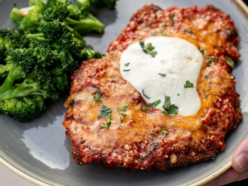 Crispy chicken parmesan with melted cheese over pasta